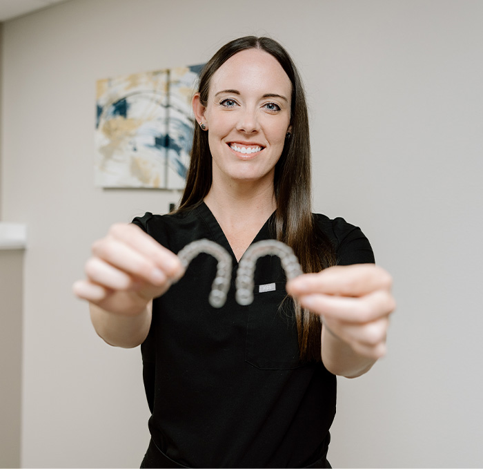 Hand holding Invisalign clear aligner in Brandon