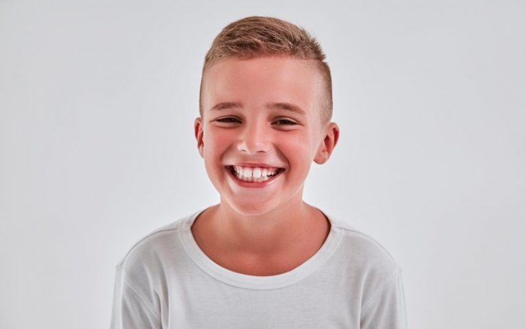 Boy in white shirt with white background smiling happily